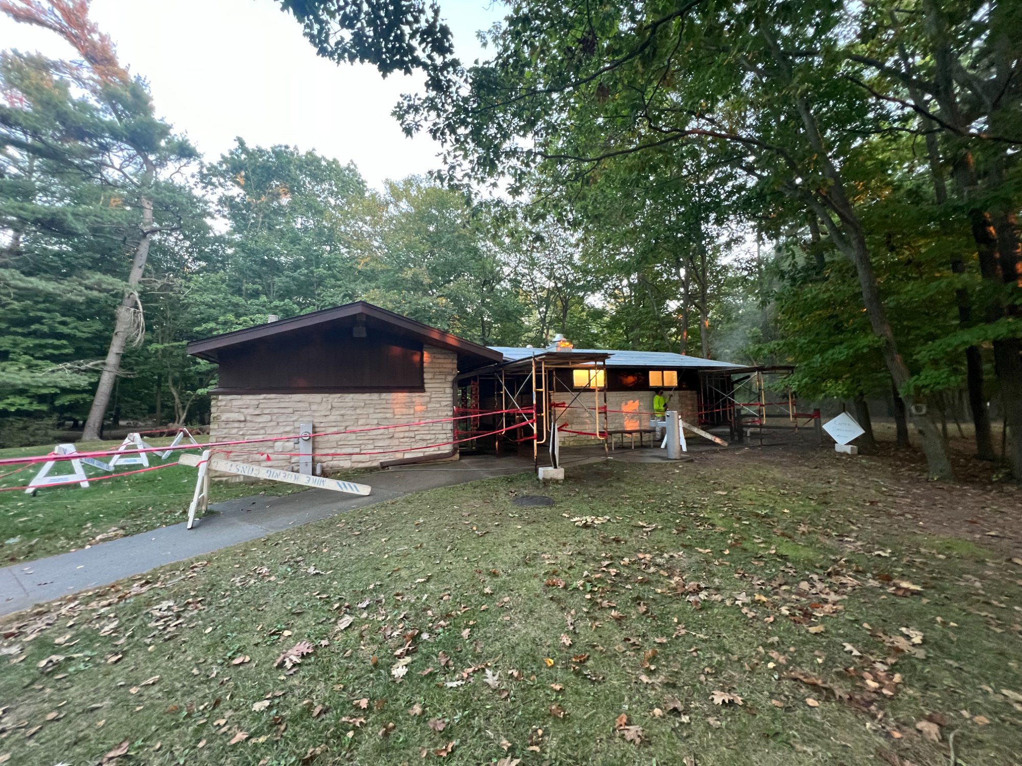 Public park building surrounded by trees with scaffolding set up during municipal painting project