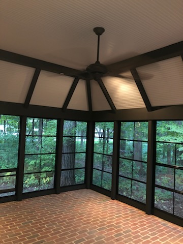 Screened porch interior with dark painted beams, window frames, and white beadboard ceiling