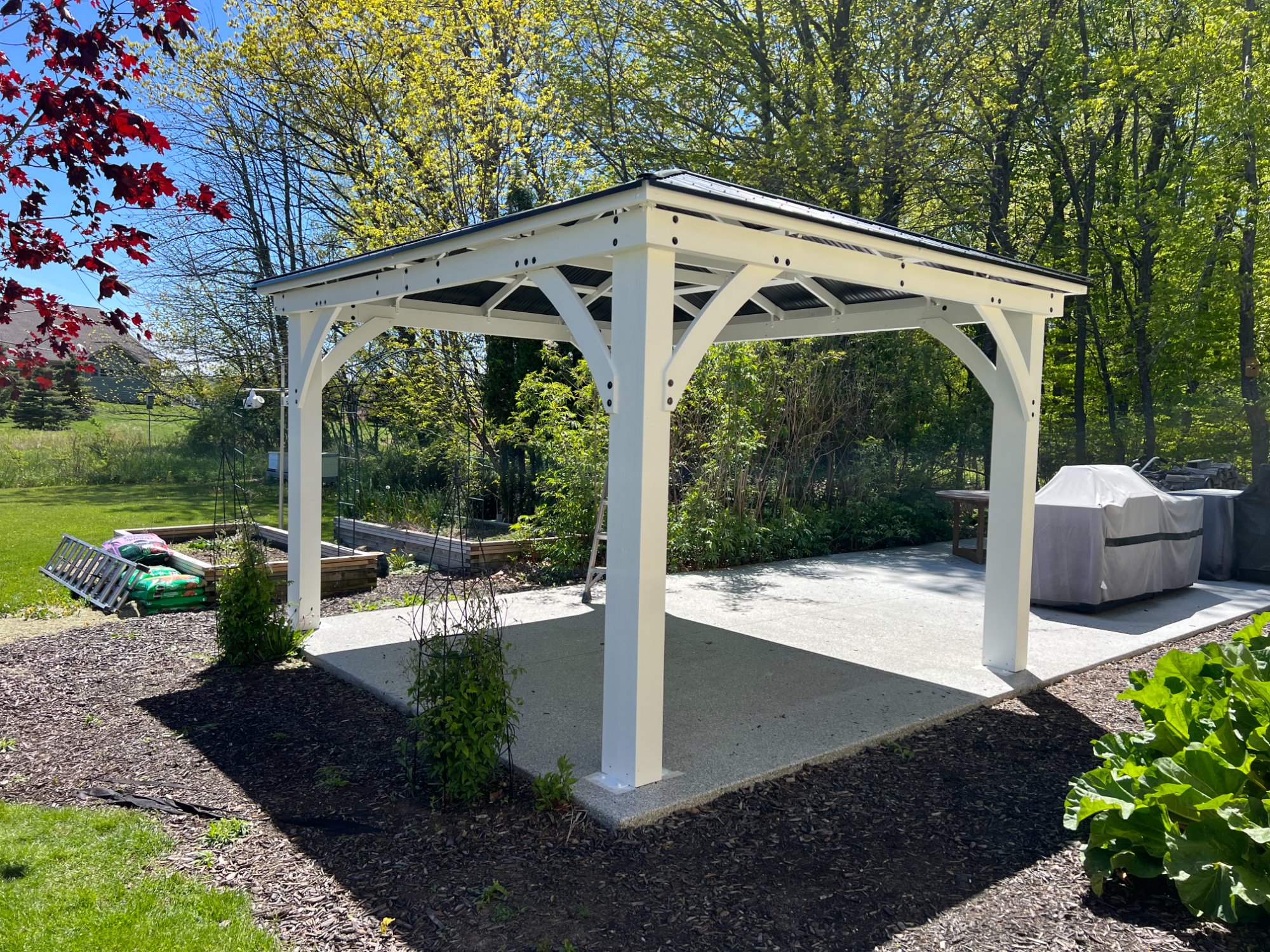 Alternate angle of white painted pavilion showing decorative support brackets and metal roof