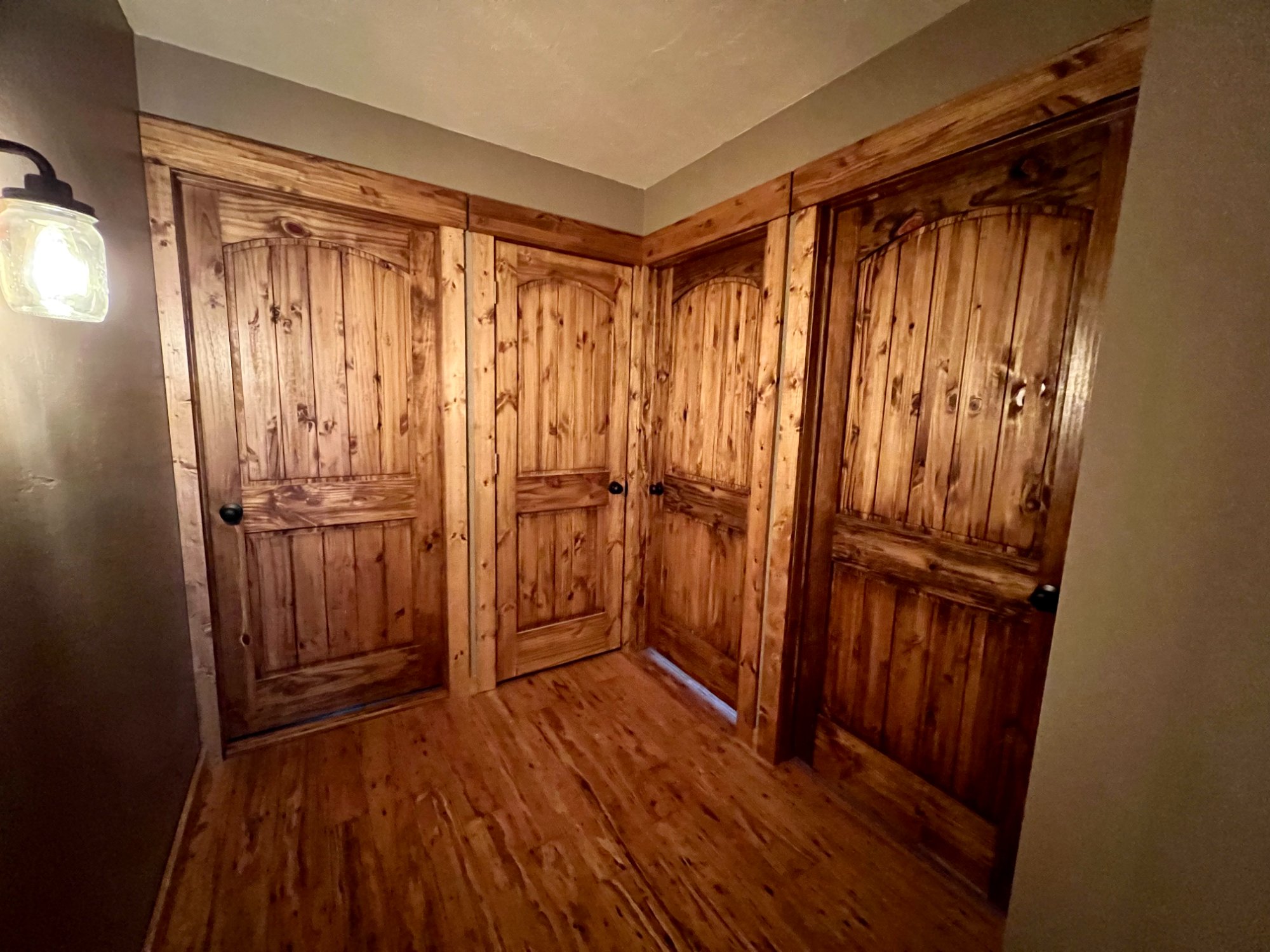 Hallway with beautifully stained knotty pine arched doors and matching hardwood floors