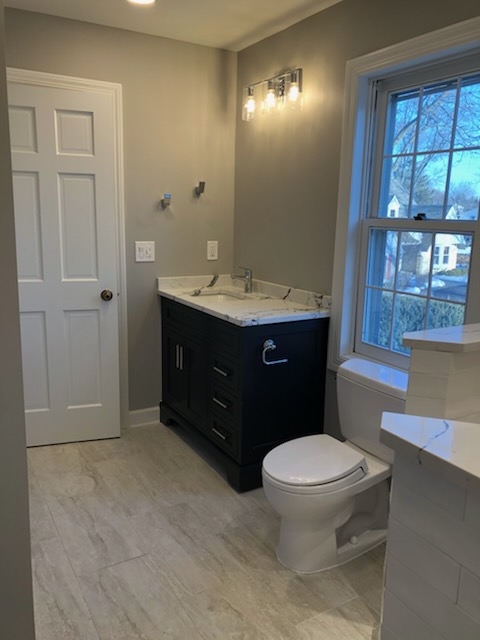 Modern bathroom with warm gray-green walls, crisp white trim, and dark vanity