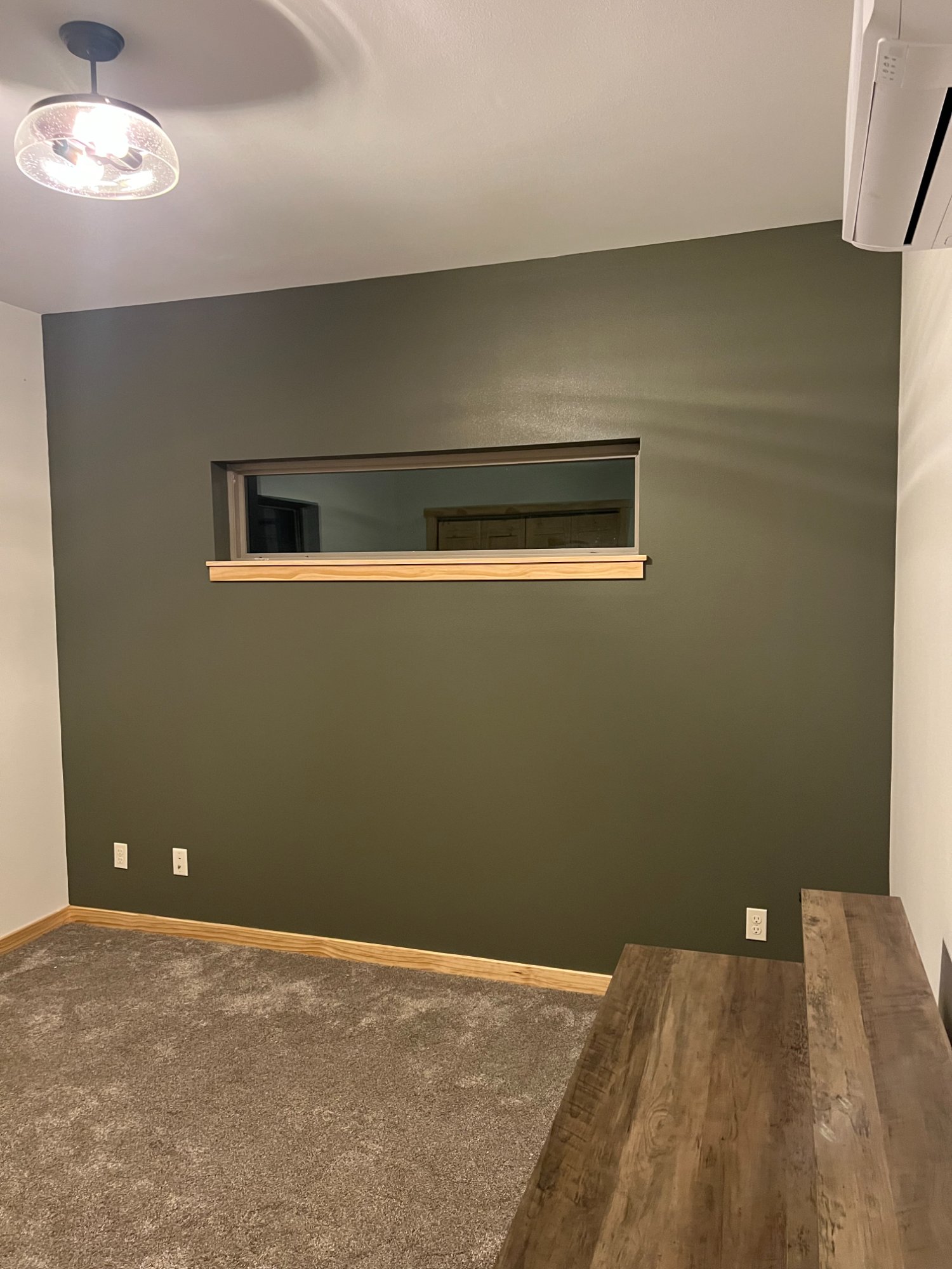 Room with dark olive green accent wall, white ceiling, and natural wood trim and baseboards