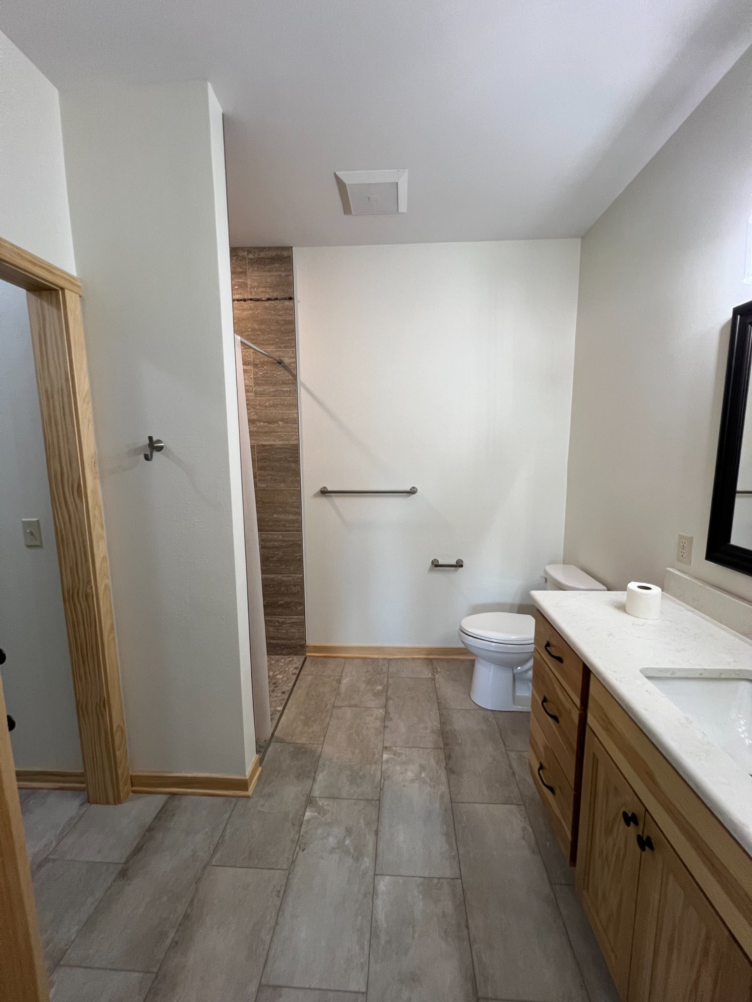 Clean freshly painted bathroom with bright white walls, ceiling, and natural wood vanity