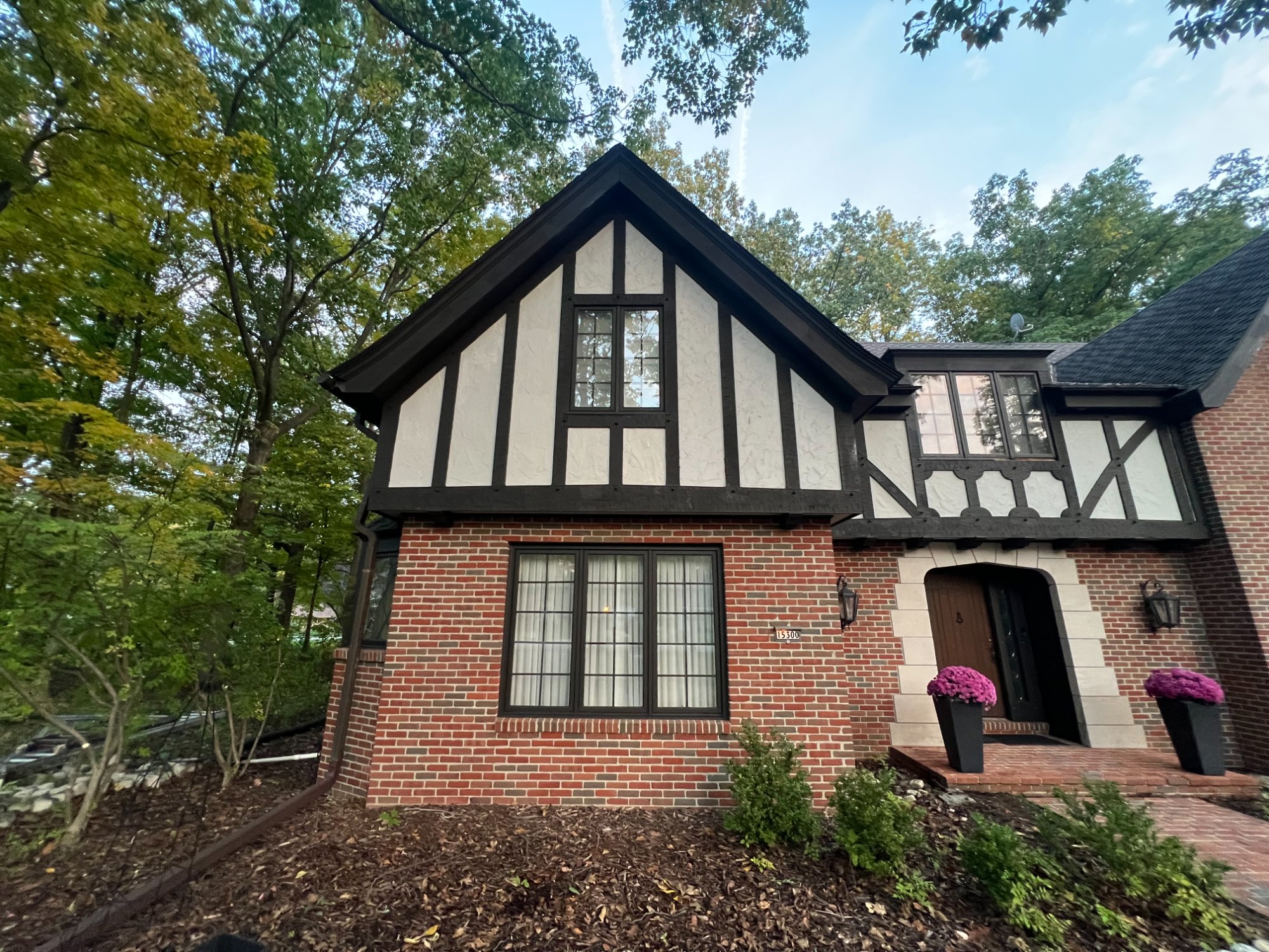 Tudor home side view showing freshly painted dark timber framing on cream stucco gable above brick