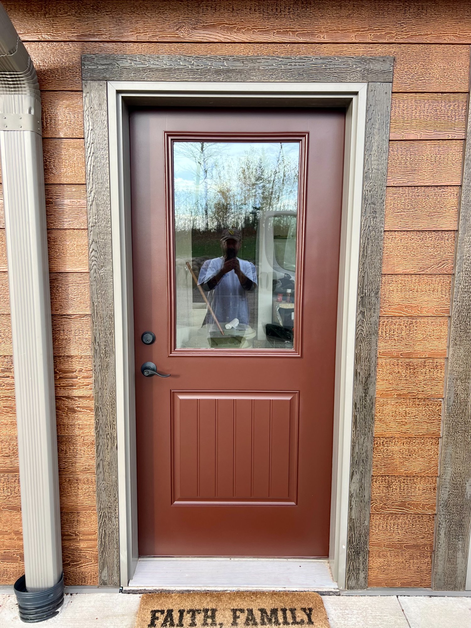 Freshly painted side entry door in rich brown on wood-sided home with clean trim