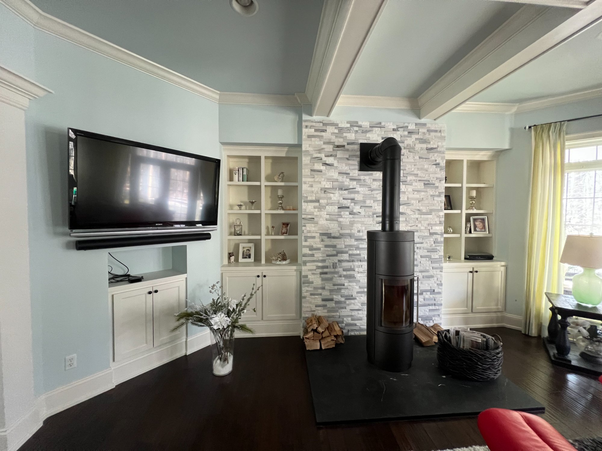 Detail view of living room showing coffered ceiling, stone fireplace, and white built-in cabinets