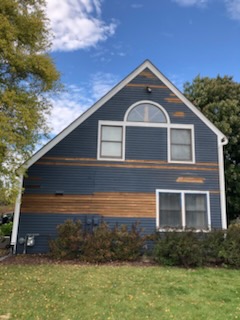 A-frame house with peeling paint and bare wood before painting in Manitowoc