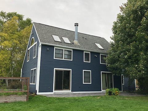 Rear view of A-frame house with navy blue siding, white trim, and skylights