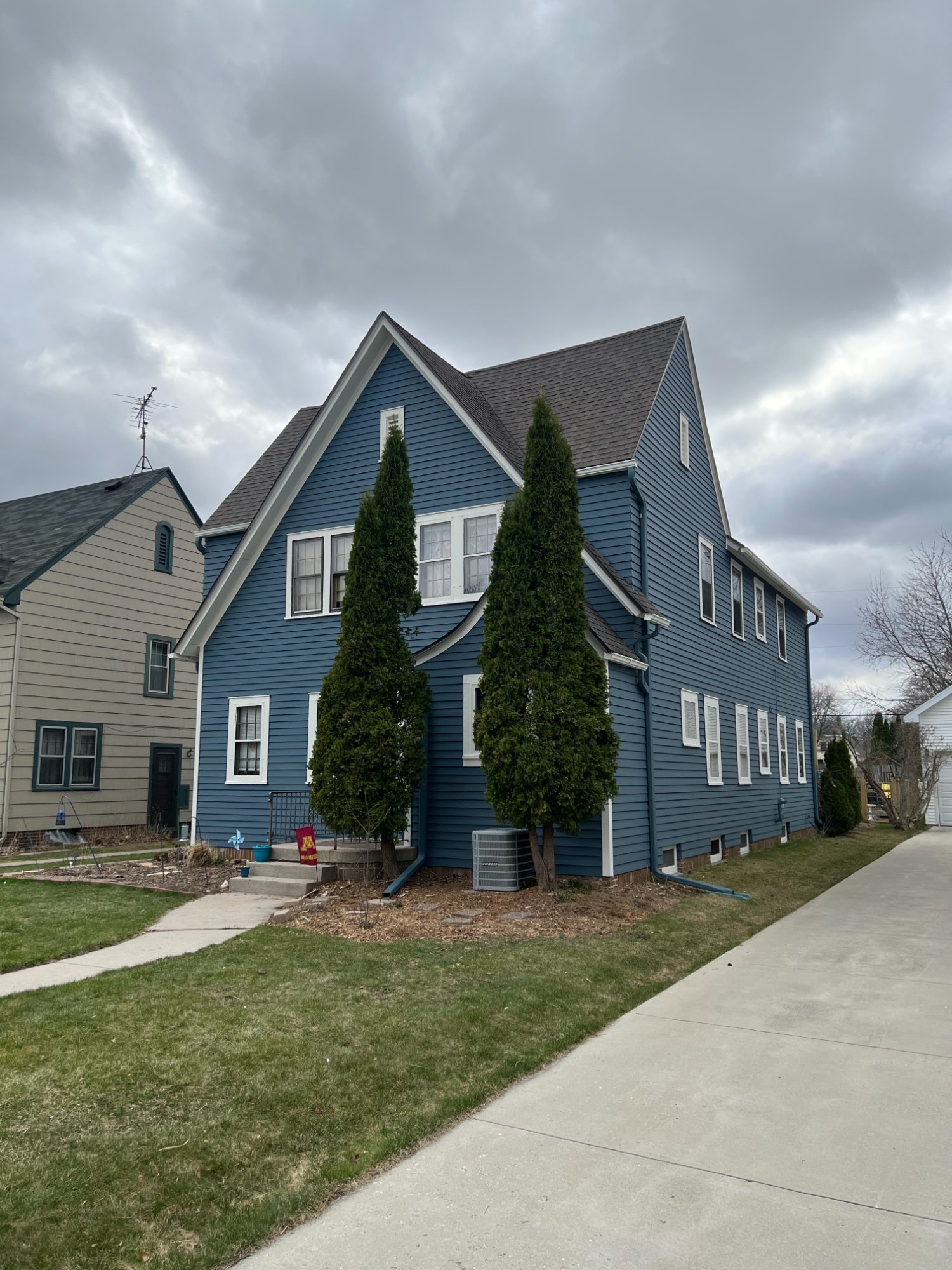 Side view of blue two-story clapboard house with white trim and driveway