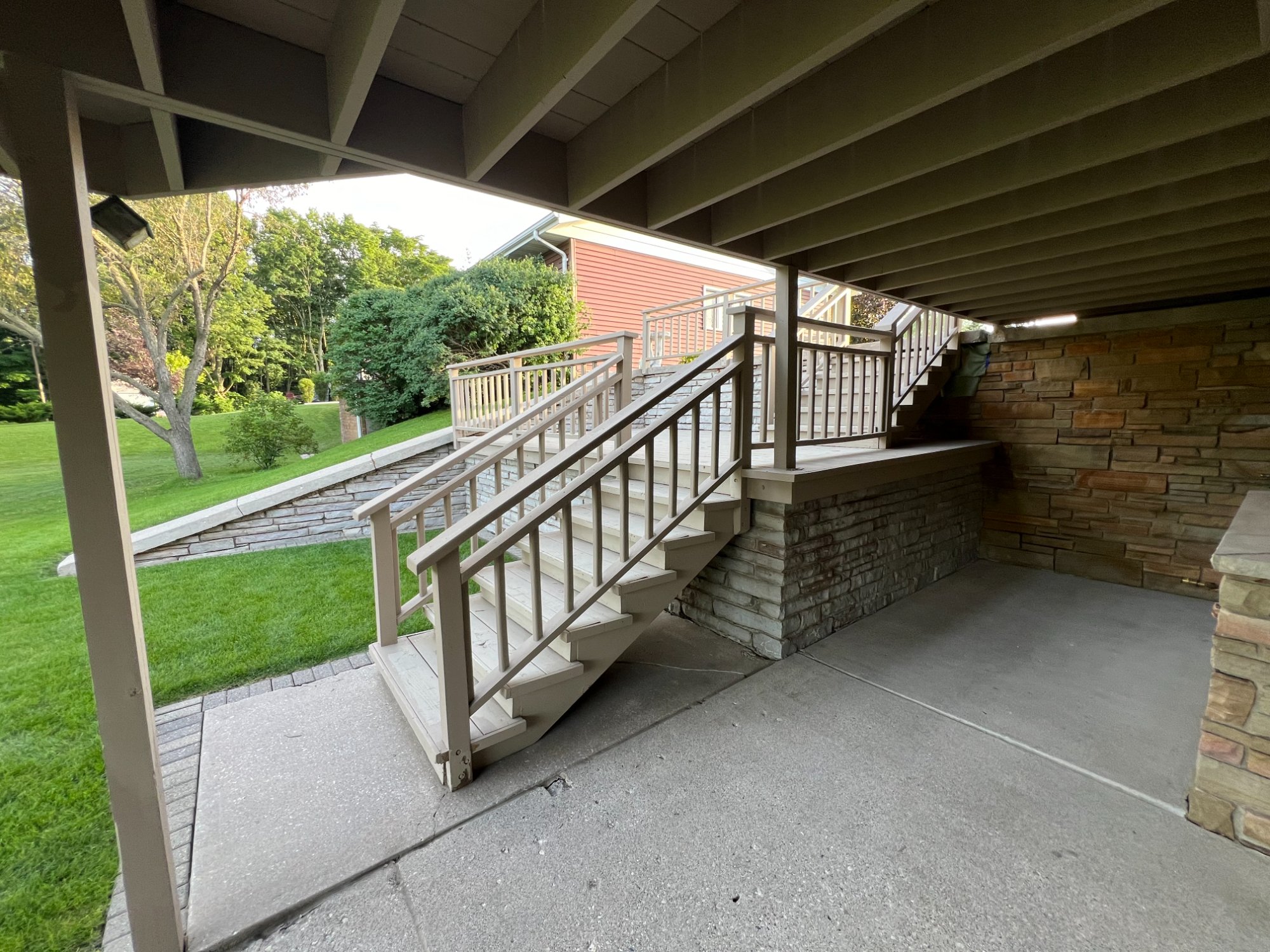 Under-deck area showing painted support beams, joists, stairs, and railings