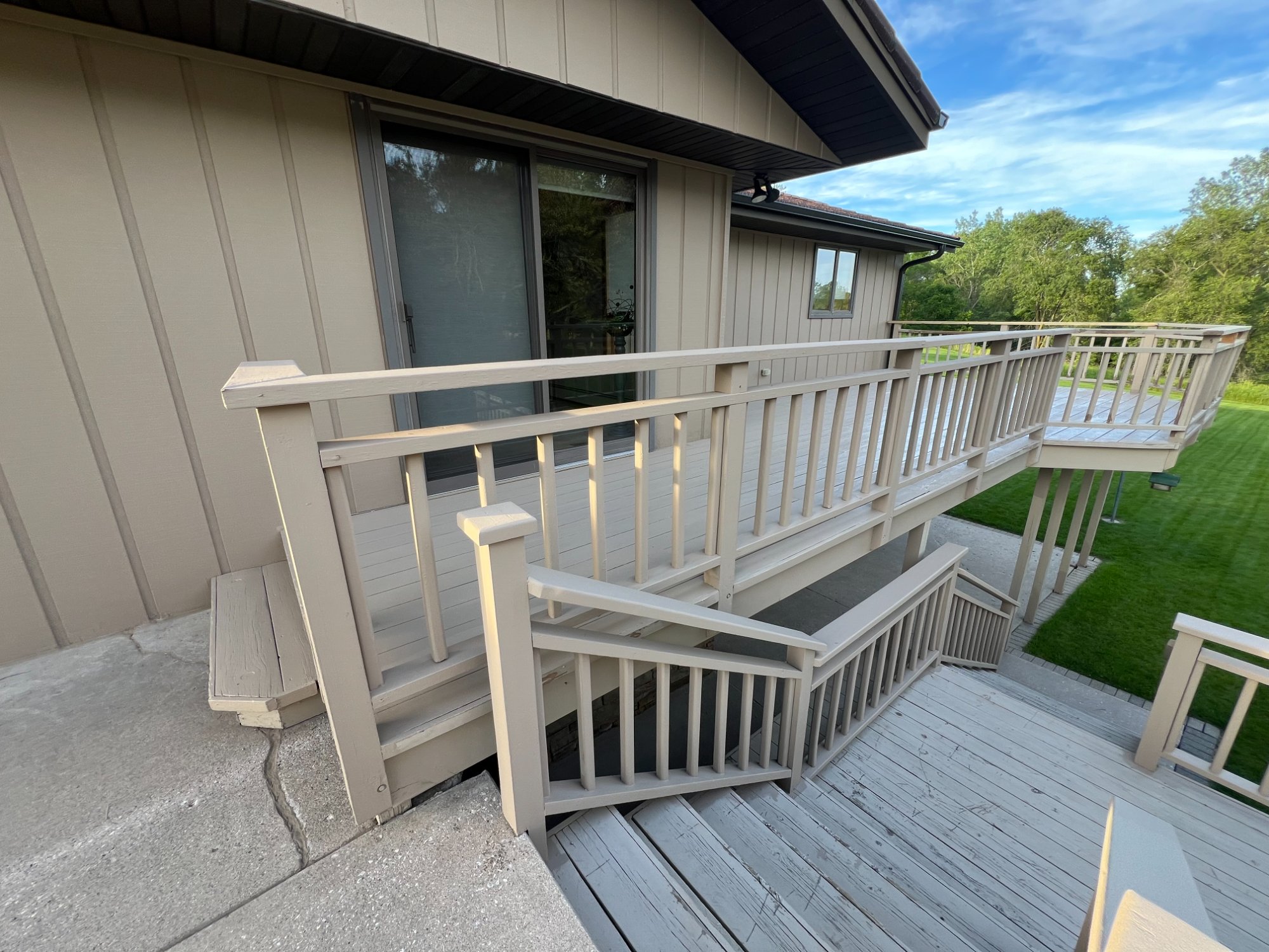 Freshly painted deck railing and stairs with matching siding and sliding door