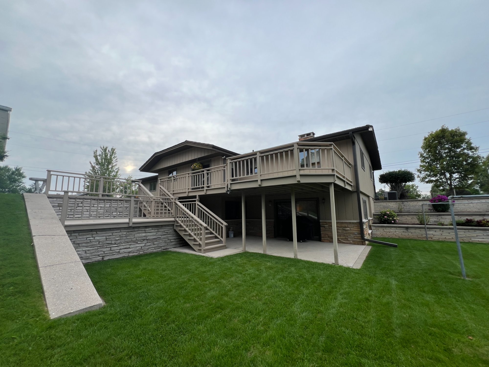 Full exterior of raised ranch home with fresh tan siding, dark trim, and stone veneer